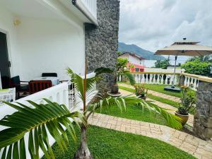 a patio with a palm tree and an umbrella at D BES Residence Self Catering in Beau Vallon