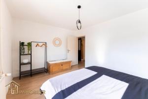 a white bedroom with a bed and a wooden floor at Colmar centre - L'Essentiel in Colmar