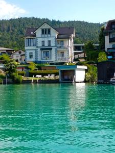 a large house sitting on top of a body of water at Seeappartements Villa Sole in Pörtschach am Wörthersee