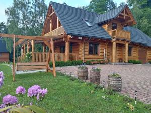 a log cabin with a porch and some flowers at U Janusza i Grażyny in Ściegny