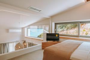 a bedroom with a bed and a flat screen tv at Gabbana Beach Villas in Syvota