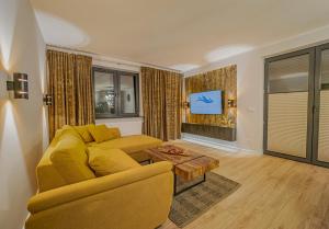 a living room with a yellow couch and a tv at Apartament w Cieplicach Platinium in Jelenia Góra