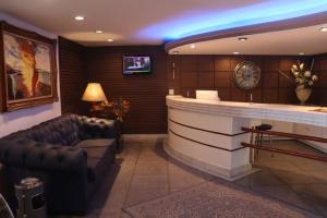a lobby with a bar with a couch and a tv at Vicenza Apart Hotel in São João del Rei