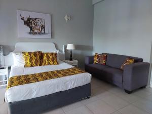 a bedroom with a bed and a couch at Fairway Guest Lodge in Margate