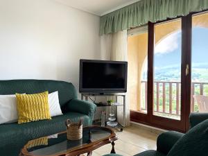 a living room with a green couch and a tv at Casona de la Loma - 2806 in San Mamés de Meruelo