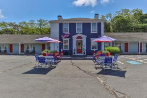 a group of chairs and umbrellas in front of a house at Olde Tavern Motel and Inn - Cape Cod in Orleans