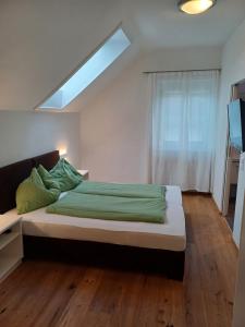 a bedroom with a bed with green sheets and a skylight at Seeappartements Villa Sole in Pörtschach am Wörthersee