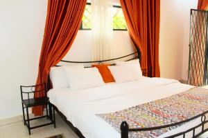 吉佳利的住宿－Salama Village Kigali，一间卧室配有带橙色窗帘的大床