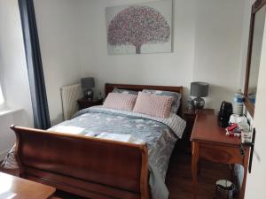 Schlafzimmer mit einem Bett mit rosa Kissen und einem Tisch in der Unterkunft Marianne Cottage Chambre d'Hotes in Couvains