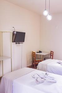 Habitación con 2 camas y TV en la pared. en Hotel Primavera Betim en Betim
