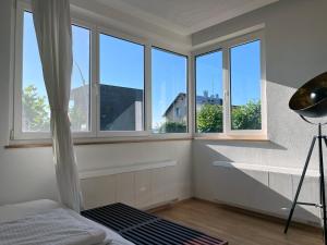 a room with three windows and a bed and a desk at Marina Studio Bregenz - See & City in Bregenz