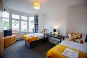 una camera con 2 letti, una scrivania e una TV di Granby Grove Townhouse - Sleeps 8- 4 Bedrooms a Southampton