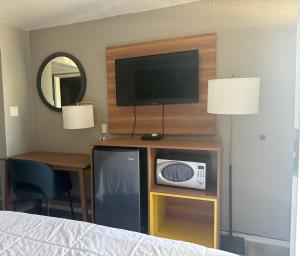 a bedroom with a tv and a desk with a bed at Days Inn & Suites by Wyndham Needles in Needles