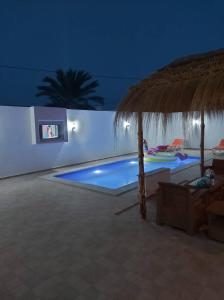 einen Swimmingpool in der Nacht mit einem Strohschirm in der Unterkunft Villa TAGUERMES in Taguermess