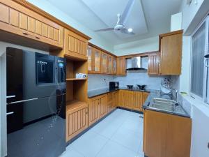 a kitchen with wooden cabinets and a black refrigerator at Luxury Holiday Home in Islamabad in Islamabad