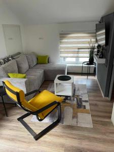 - un salon avec un canapé et un fauteuil jaune dans l'établissement Dolly Zlatibor, à Zlatibor