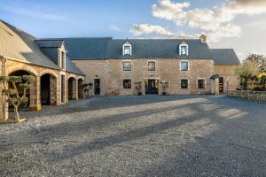 a large brick building with a large driveway at La Roulotte de la Trigalle in Valognes