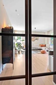 vista su un soggiorno attraverso una porta scorrevole in vetro di Stor leilighet med 4 soverom,stor terrasse og hage a Fornebu