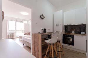 a kitchen with white cabinets and white stools at MaKi apartment in Belgrade