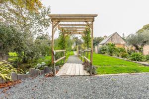 a wooden walkway in a garden with a gazebo at La Roulotte de la Trigalle in Valognes