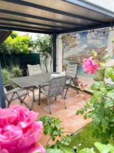 a patio with a table and chairs and pink roses at Aubing Süd in Munich