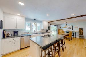 eine große Küche mit weißen Schränken und einem Tisch in der Unterkunft The Blue Whale Cottage in Brewster