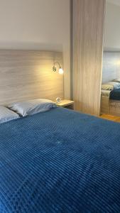 a bedroom with a large bed with a blue blanket at Comfort Central Point apartment in Podgorica +4 photos
