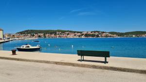 a bench sitting next to a body of water with a boat at Apartments Valentina Tisno in Tisno
