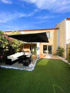 a patio with an umbrella and a green lawn at Maison avec piscine, climatisée, proche plage in Roquebrune-sur-Argens