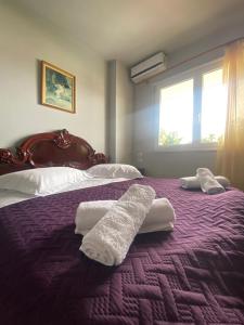a bedroom with two white towels on a purple bed at Stay the Night Shkodra Apartment City Centre in Shkodër