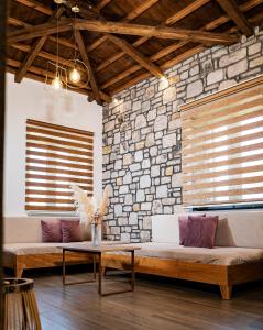- un salon avec deux canapés et un mur en pierre dans l'établissement Lithoessa Luxury Apartments, à Agios Ioannis Kaspaka