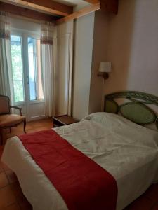 a bedroom with a bed and a chair and a window at Charmante maison avec jardin in Manosque