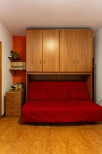 1 dormitorio con cama roja y armarios de madera en appartamento a 50 mt dal mare, en Porto SantʼElpidio