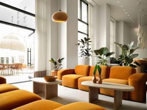 a living room with orange couches and tables at Sandbourne Santa Monica, Autograph Collection in Los Angeles