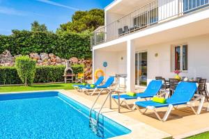 una casa con piscina y sillas azules en Villa Grace by Villa Plus, en Es Mercadal