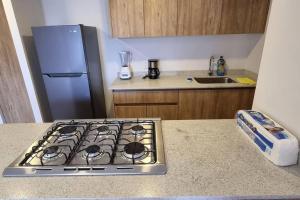 a kitchen with a stove top oven next to a refrigerator at Hermoso departamento cerca del Auditorio Telmex in Guadalajara