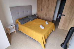 a small bedroom with a bed with a yellow bedspread at Hermoso departamento cerca del Auditorio Telmex in Guadalajara