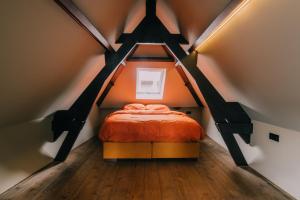 a bedroom with an orange bed in a attic at TheBridge29 boutique apartment in Breda