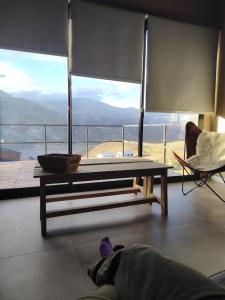 a person laying in a room with a table and a chair at Cabañas de Montaña Armonías Lodge in Los Molles