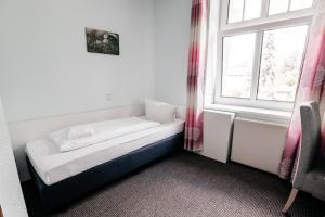 a small bed in a room with a window at Hotel am Fluss in Heidesee