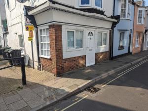 a small brick building with a white door on a street at Free Parking, 1 bed flat Park street in Weymouth