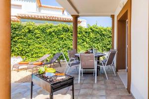 een patio met een tafel en stoelen en een heg bij Villa Primula by Villa Plus in Beniarbeig