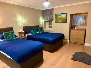 a bedroom with two beds with blue sheets and a dresser at The Milton Accommodation in Elgin