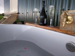 bañera con botella de vino y 2 copas en Cosy Shepherds hut in Carmarthen, en Llanfynydd