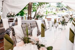 a table with white chairs and flowers on it at Hotel am Fluss in Heidesee