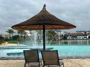 2 sillas y una sombrilla frente a la piscina en The Blyde Crystal Lagoon, en Pretoria