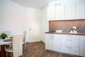 a kitchen with white cabinets and a dining table at Cykloapartmány Znojmo in Znojmo +3 photos