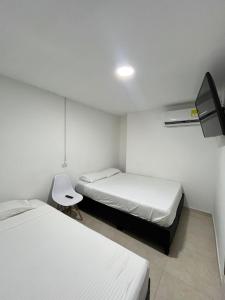 Habitación con 2 camas y una silla. en Hotel Lago Boutique, en Cartagena de Indias