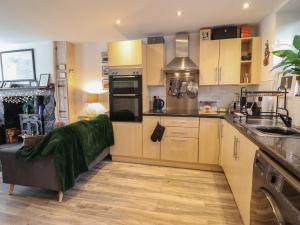 a kitchen with wooden cabinets and a couch in it at 3 Barlwyd Terrace in Blaenau-Ffestiniog