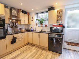 a kitchen with wooden cabinets and a washer at 3 Barlwyd Terrace in Blaenau-Ffestiniog +15 photos